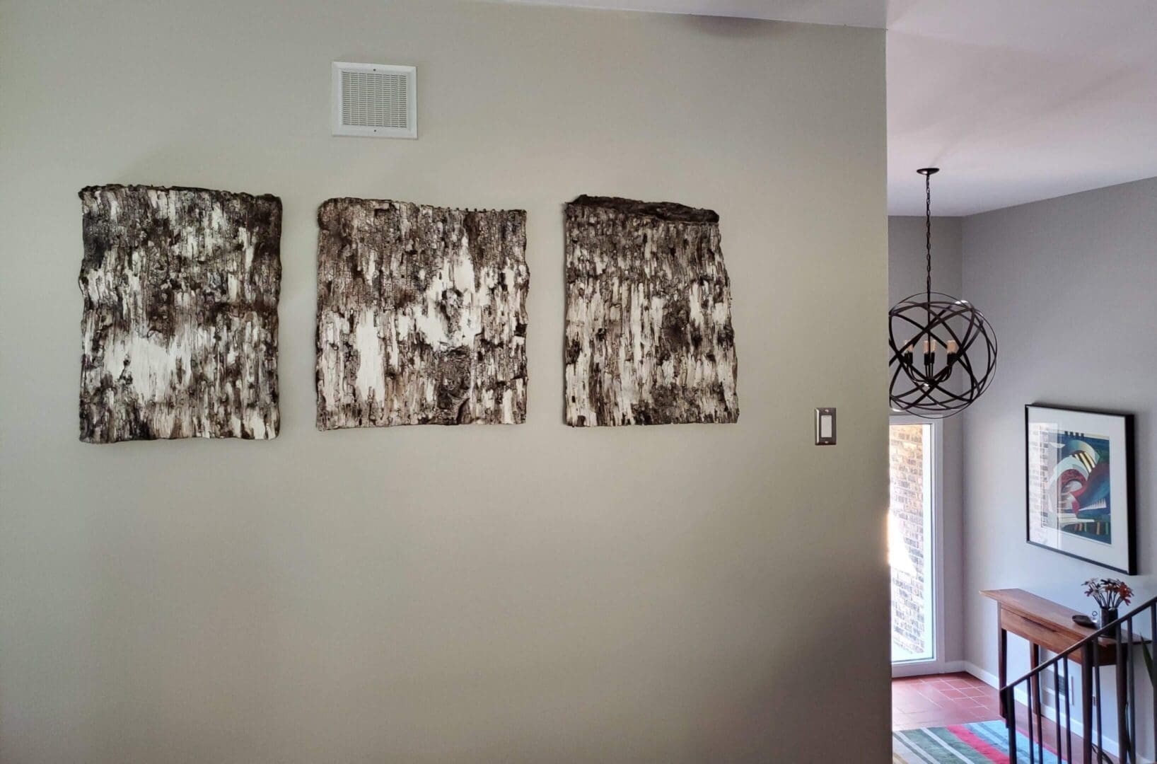 Three textured metal wall art pieces arranged horizontally on a beige wall.