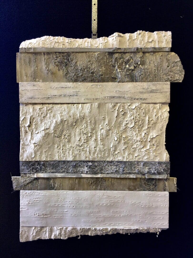 A textured stone and plaster wall with horizontal metal bands.