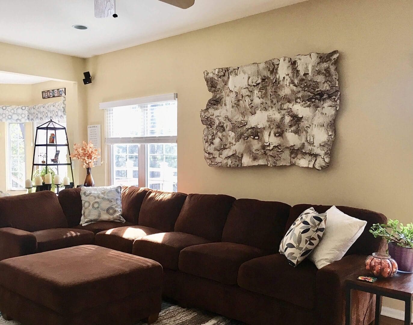 Cozy living room with a brown sectional sofa and abstract wall art.