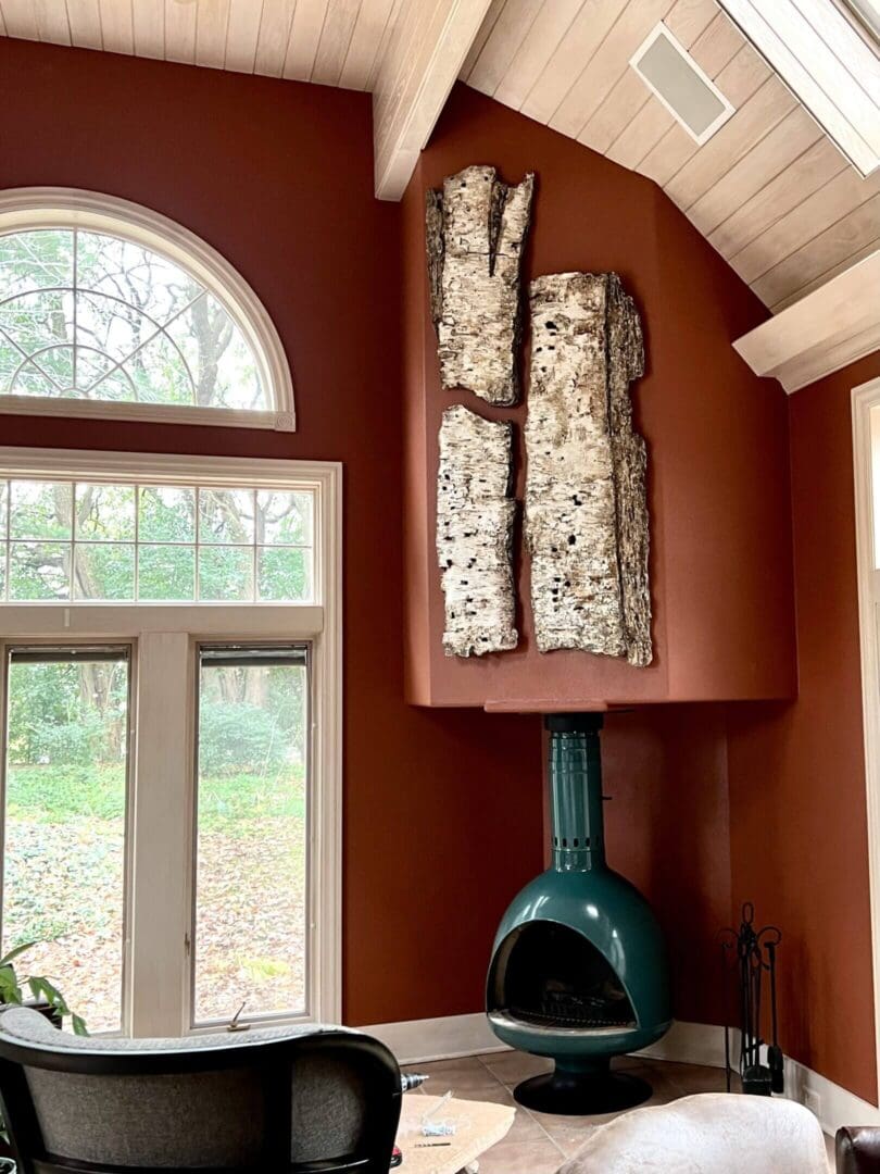 Unique wood art mounted above a vintage green fireplace in a cozy room.