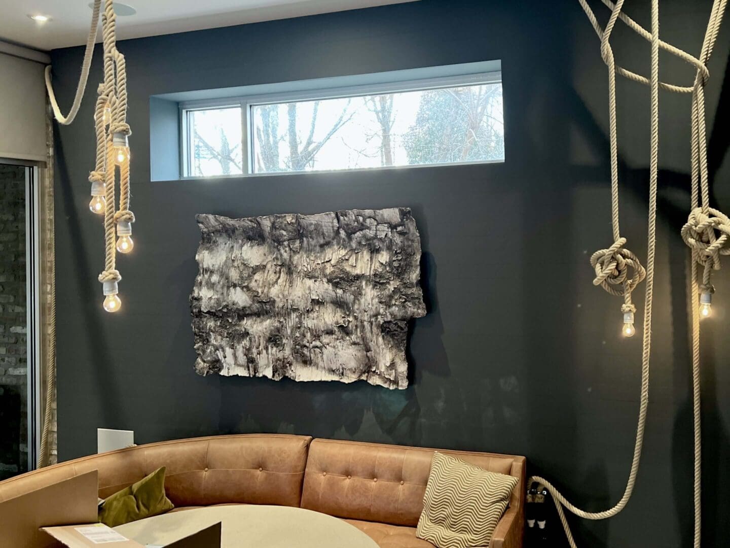 Modern living room with dark walls and abstract art.