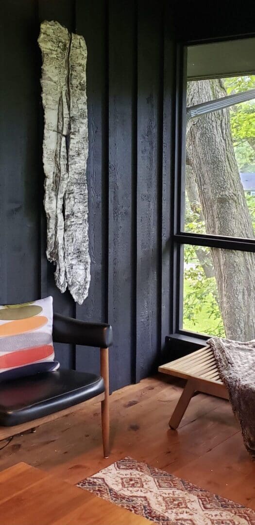 Cozy corner with a textured wall art and a striped chair near a window.