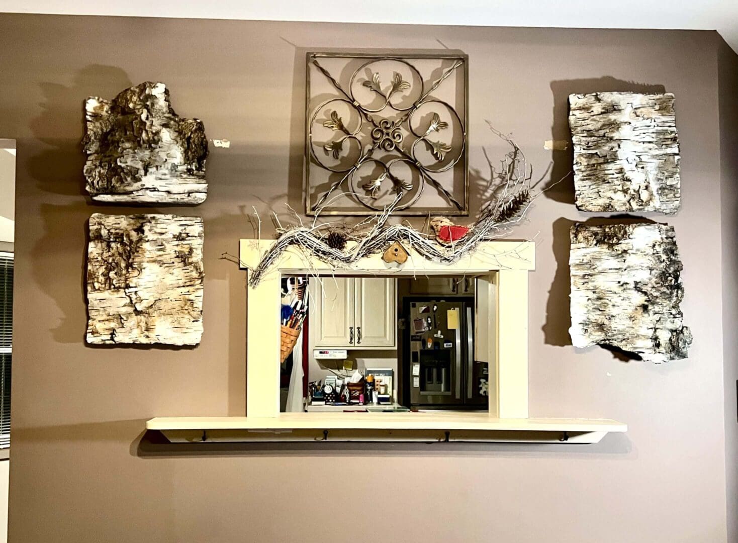 Interior wall with decorative art and a pass-through window to a kitchen.