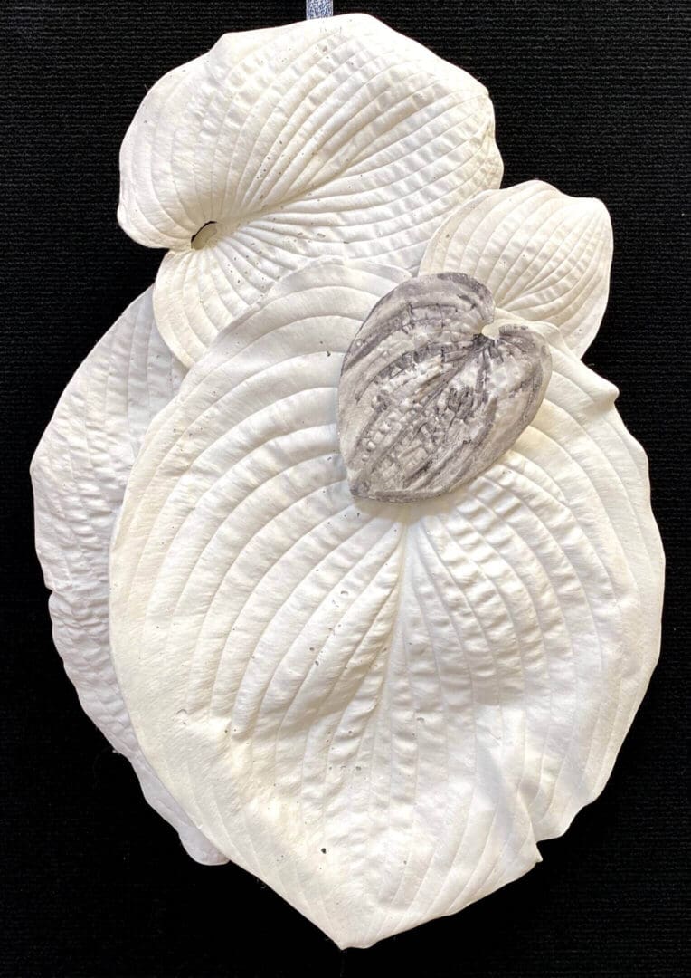 A white leaf sculpture with a detailed beetle on top.