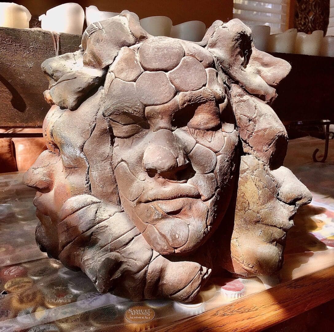 A detailed clay sculpture of a human face with a textured headdress.