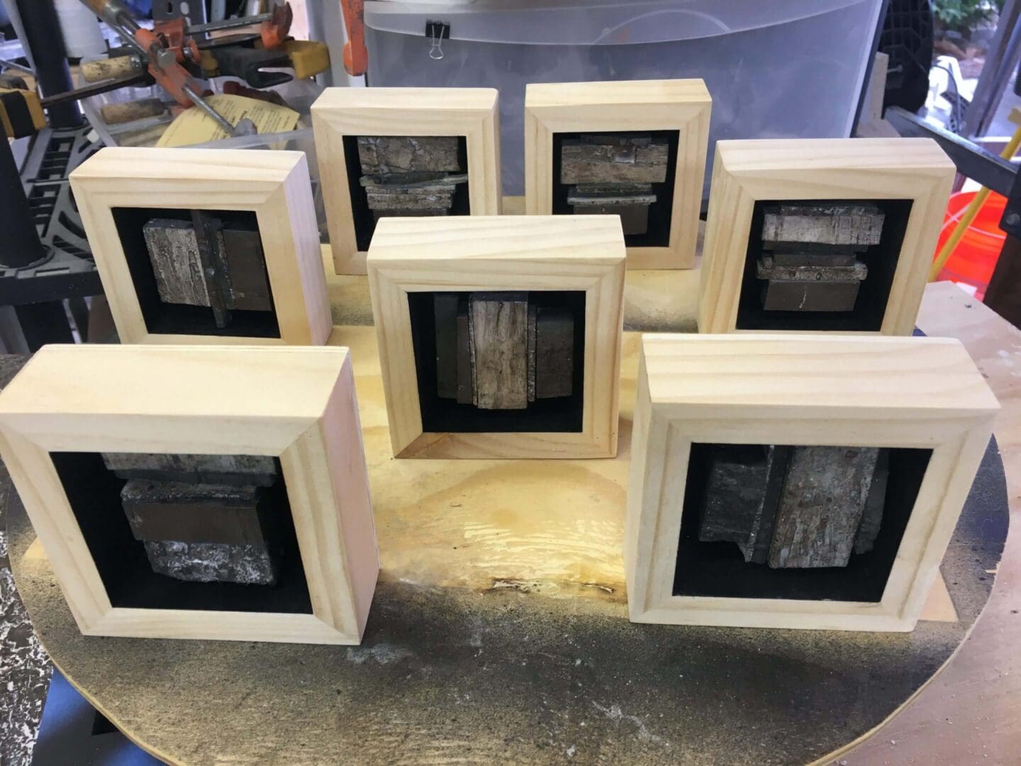 Seven framed artworks displayed on a table with wooden borders.