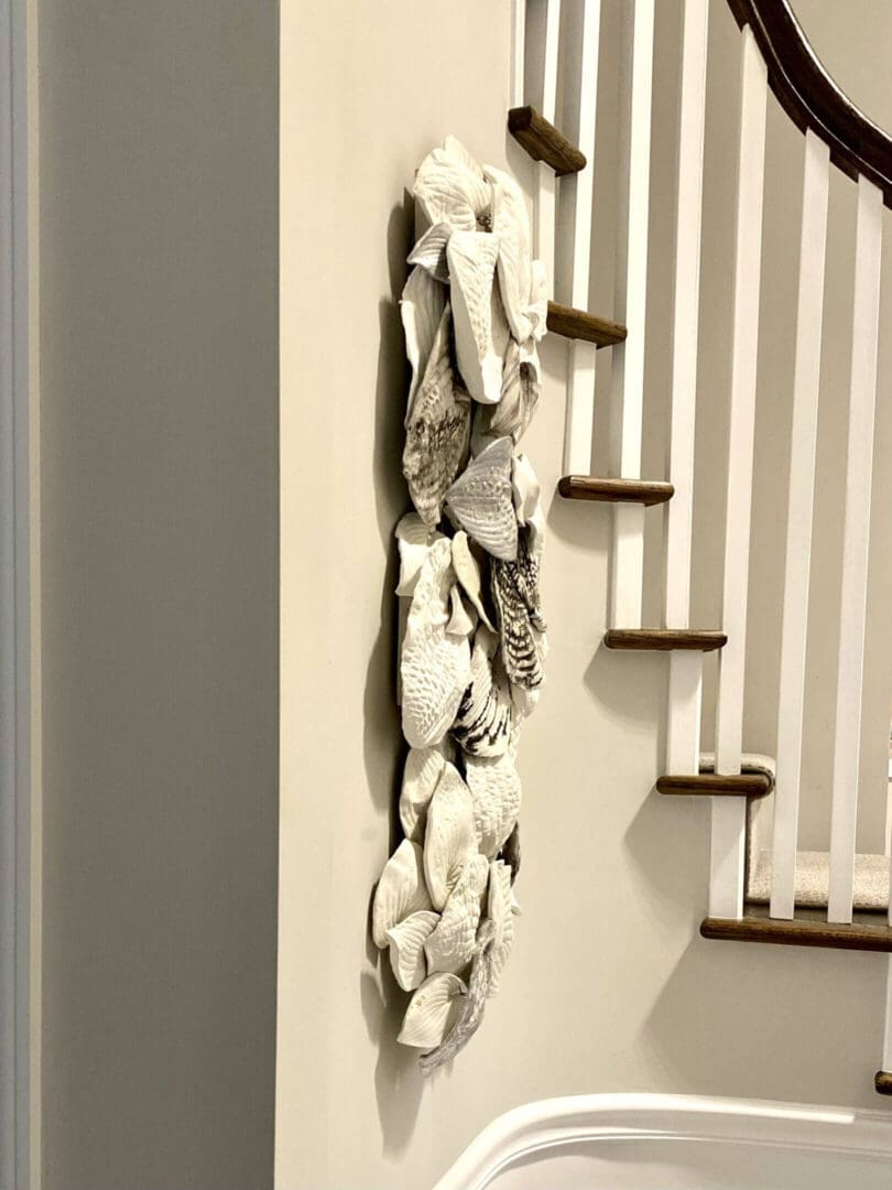 Decorative wall art featuring white floral designs beside a staircase.