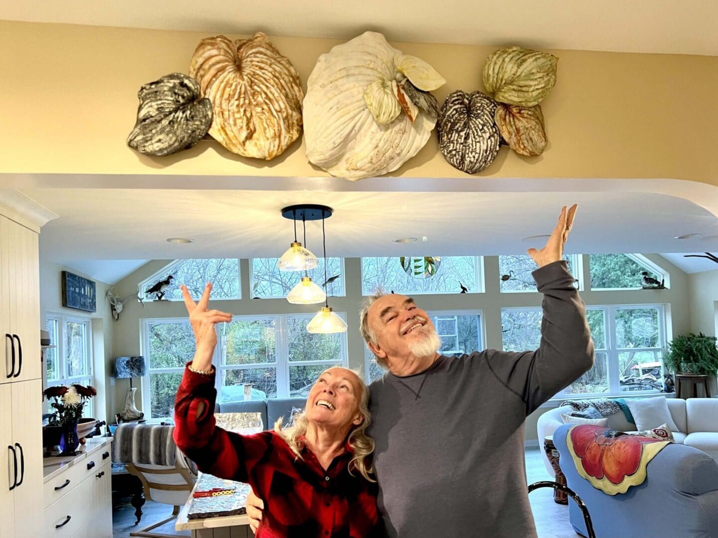 Elderly couple joyfully reaching up in a cozy living room.