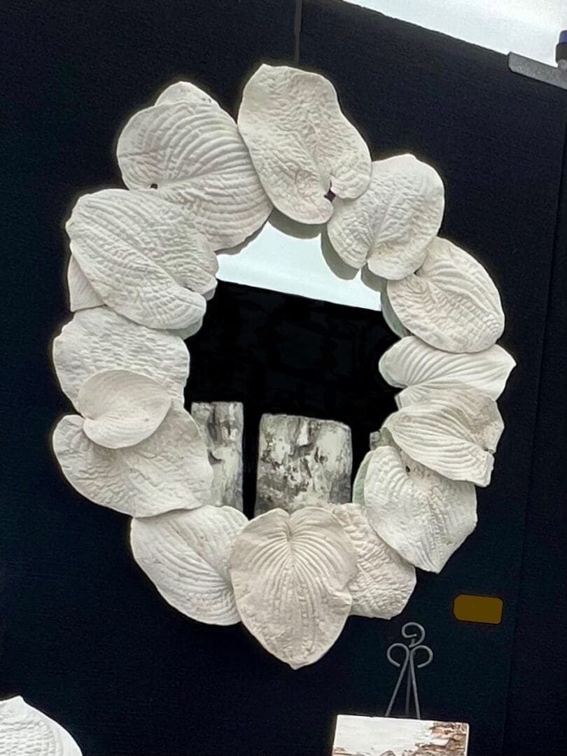 A mirror framed with white, petal-like textured pieces.