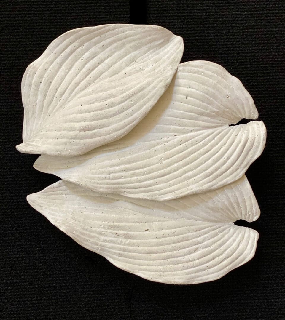 White textured leaves-shaped ceramic plates on a black surface.