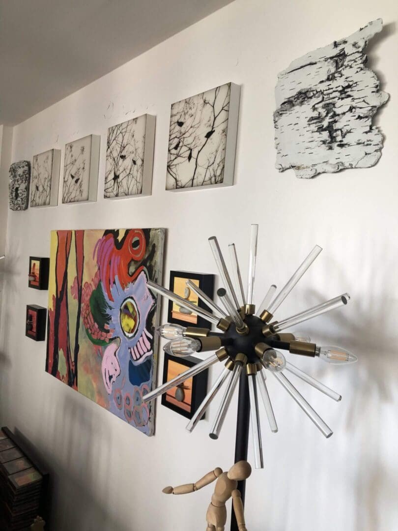Eclectic art display with paintings and a modern spiked chandelier.