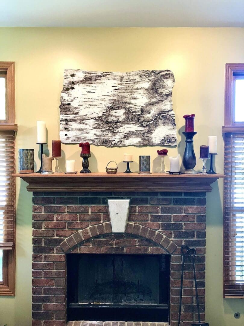 A brick fireplace with decorative vases and modern abstract art above.