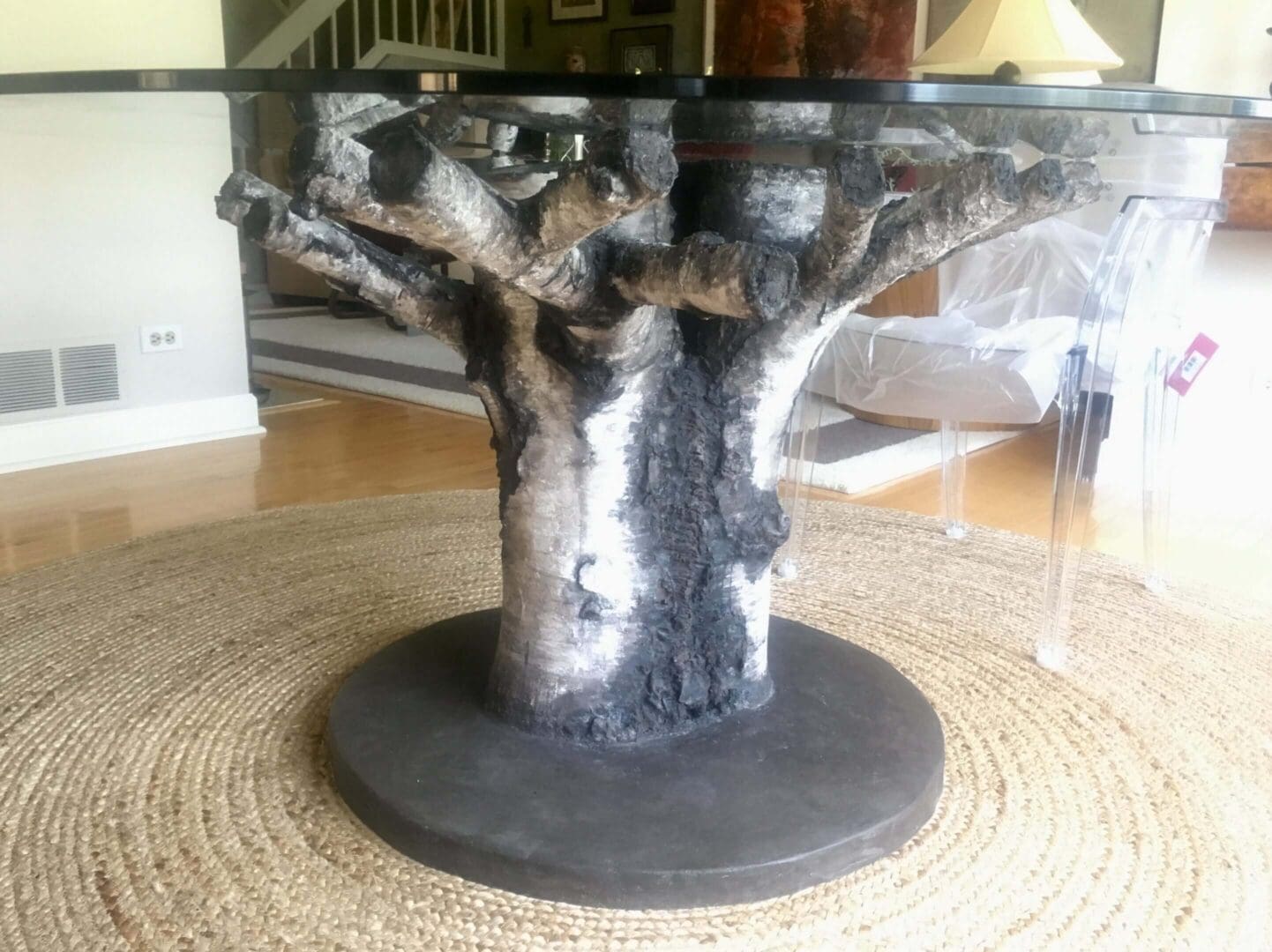 A unique tree-shaped sculpture with a textured metallic finish on a round base.